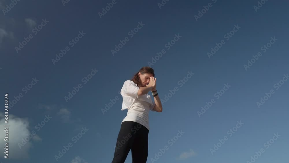 Wellbeing. Young caucasian woman doing on the rocky shore. Blue sky in the background. High quality 4k footage Wellbeing. Young caucasian woman doing on the rocky shore. Blue sky in the background. High quality 4k footage