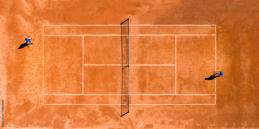 View from above, aerial view of two people playing tennis on a clay court during the Coronavirus (Covid-19) outbreak.