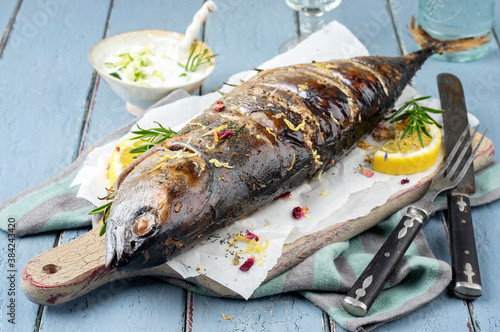 Traditional Australian barbecue bonito fisch with tzatziki and lemon slices offered as closeup on a rustic wooden board photo