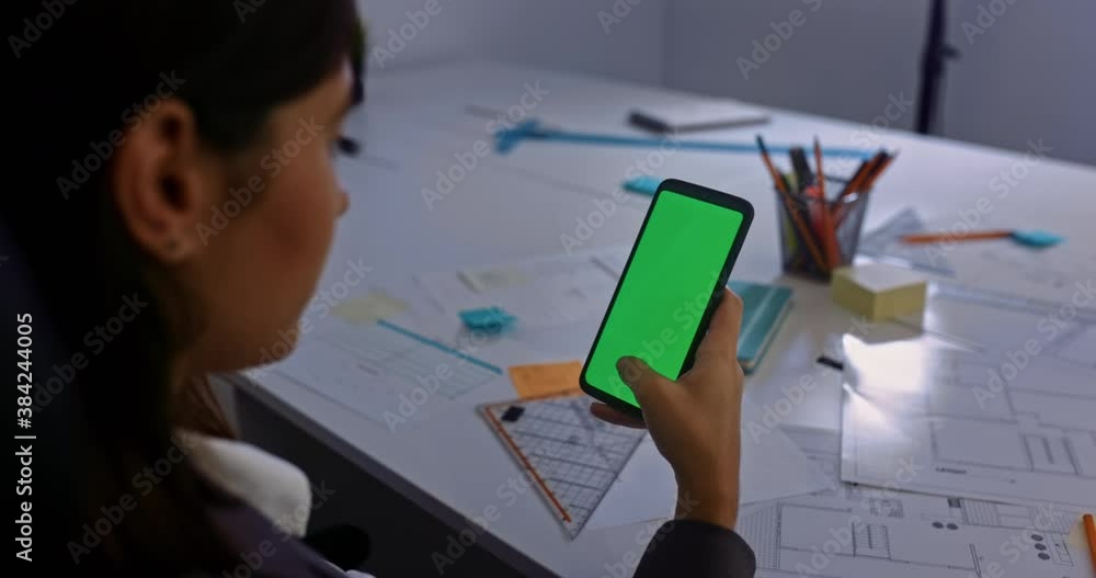 Business woman scrolling through smartphone green screen at her office Business woman scrolling through smartphone green screen at her office
