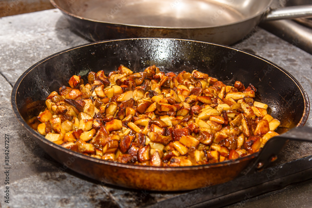 Wild mushrooms are fried in a frying pan in a restaurant