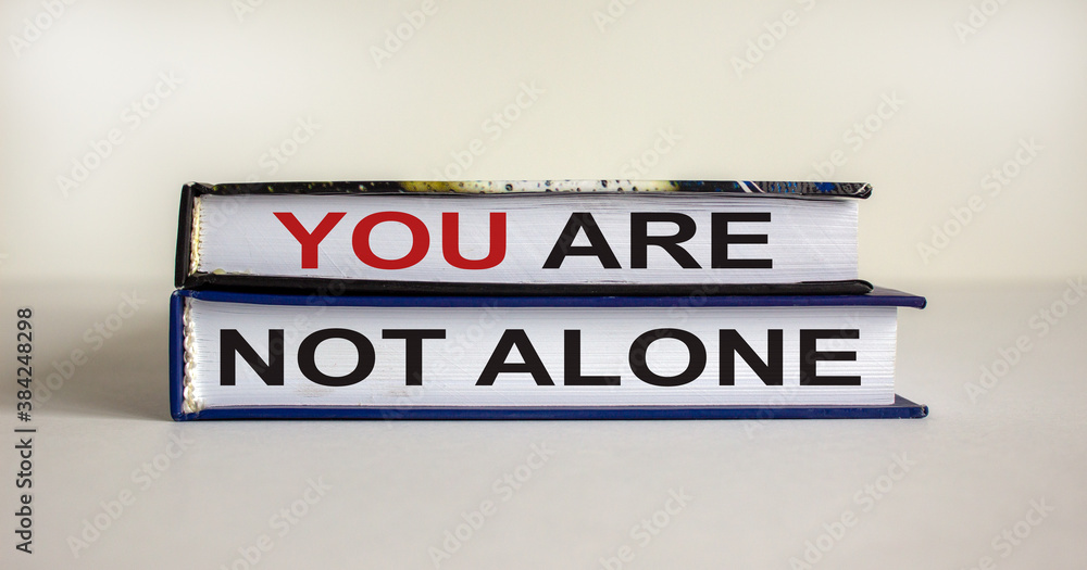 Books with text 'you are not alone' on beautiful white background. Business concept. Copy space.