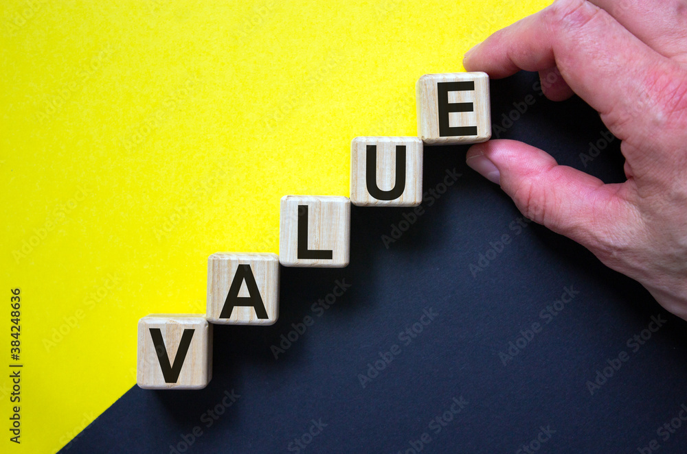 Obraz premium Wood cubes with word 'value' stacking as step stair on paper yellow and black background, copy space. Male hand. Business concept success process.