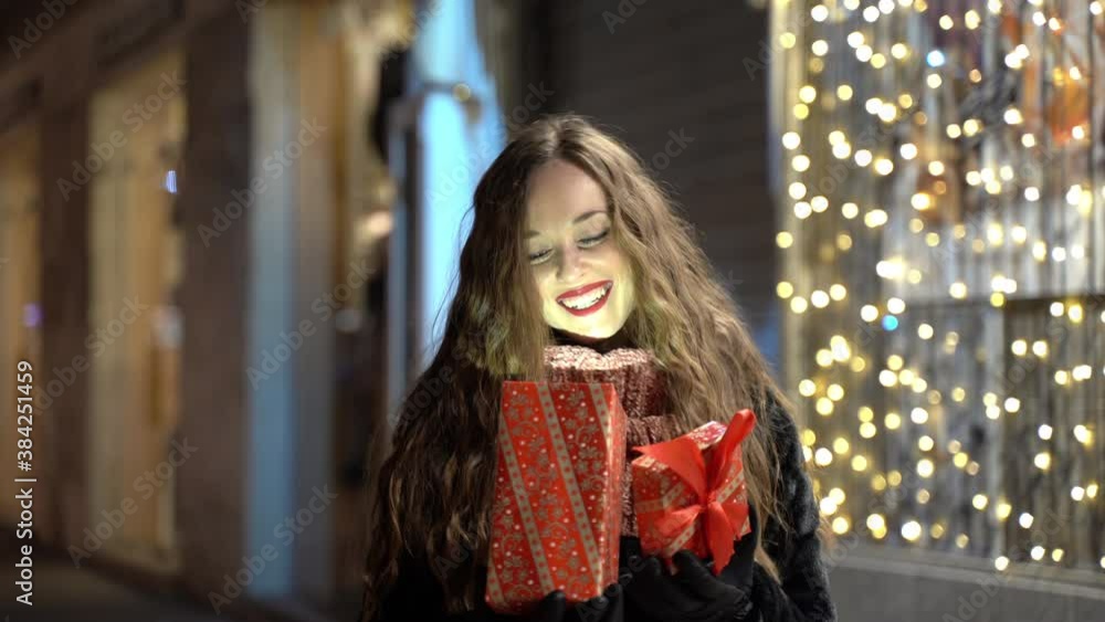 Portrait of amazing young woman on glowing christmas lights background opening special long-awaited xmas present and smiling, happy ffemale showing her real sincere emotions after receiving christmas Portrait of amazing young woman on glowing christmas lights background opening special long-awaited xmas present and smiling, happy ffemale showing her real sincere emotions after receiving christmas