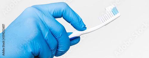 Doctor's hand in a blue medical glove holds a toothbrush Isolated on a white. dentistry. toothpaste on a toothbrush. oral hygiene. healthy teeth