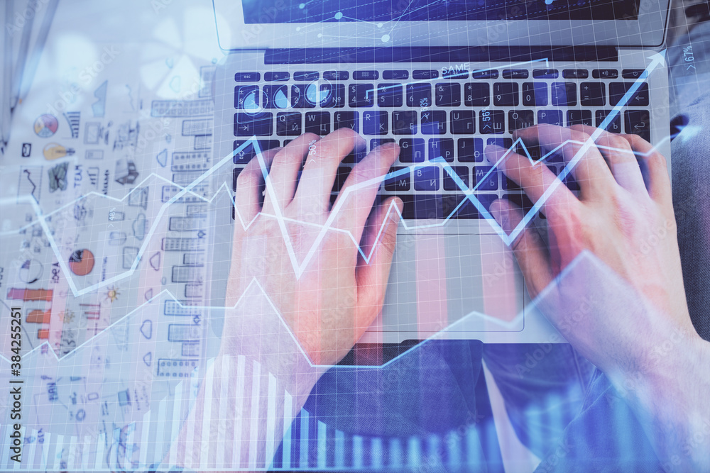 Double exposure of man's hands typing over laptop keyboard and forex chart hologram drawing. Top view. Financial markets concept. Double exposure of man's hands typing over laptop keyboard and forex chart hologram drawing. Top view. Financial markets concept.