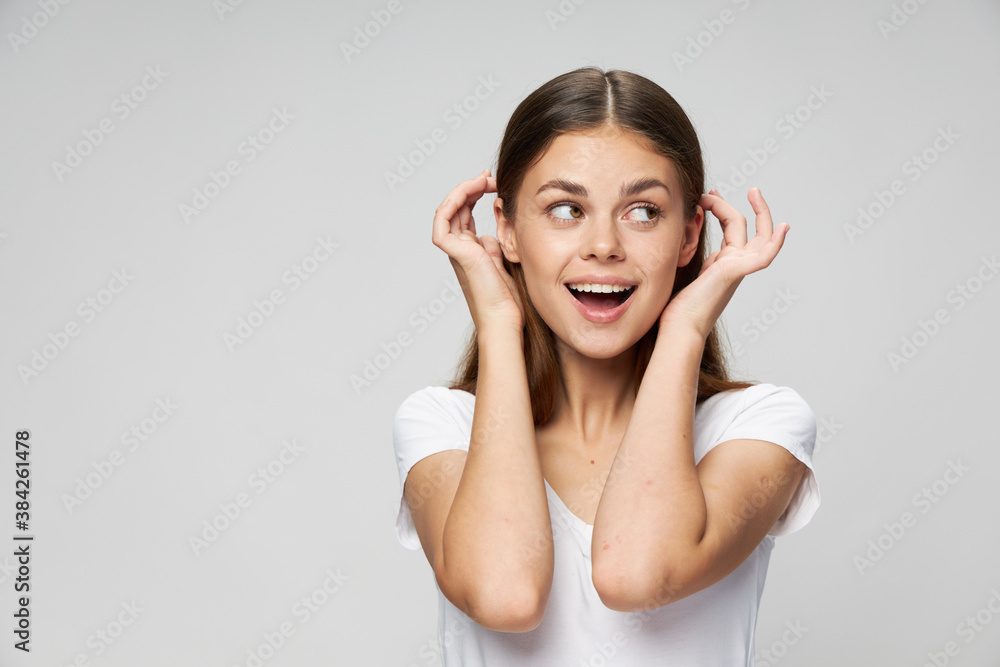 A woman with an open mouth looks to the side straightens her hair A woman with an open mouth looks to the side straightens her hair