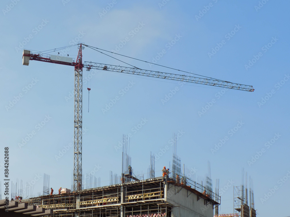 Grúa junto a edificio en construcción con albañiles Grúa junto a edificio en construcción con albañiles