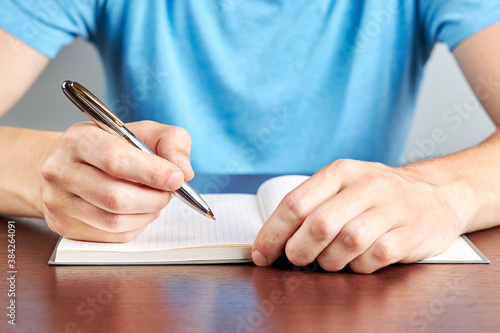 caucasian male person writing to diary or notepad. close up. office paperwork concept. planning concept.person dressed casual clothes
