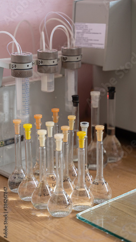 Row of many measure volume flasks  on a wooden table of an old soviet laboratory photo