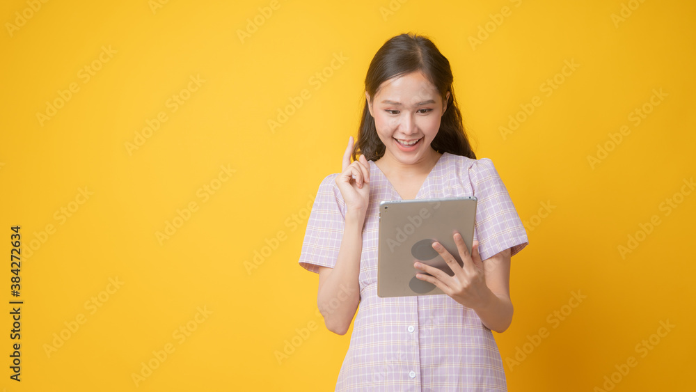 portrait Asian woman, Thai girl use tablet with big smiled on yellow studio background, technology concept portrait Asian woman, Thai girl use tablet with big smiled on yellow studio background, technology concept