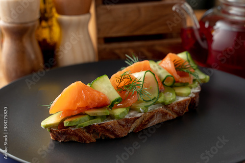 Close up of rye bruschetta with cream cheese, vegetables and smoked salmon on a long slice of grilled crunchy toast