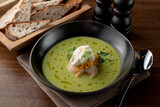 Gourmet pea soup with crab meat and shrimps on wooden table in a fancy restaurant