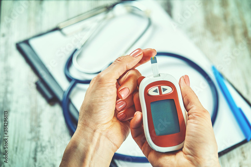 diabetic woman using blood glucose meter, female hands hold lancet pen glucometer on finger measure sugar check insulin