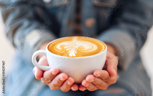 Closeup image of a woman holding a white cup of coffee