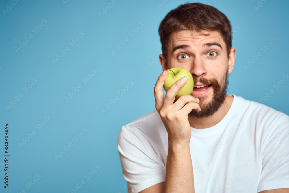 An energetic man with a green apple on a blue background gestures with his hands Copy Space emotions An energetic man with a green apple on a blue background gestures with his hands Copy Space emotions
