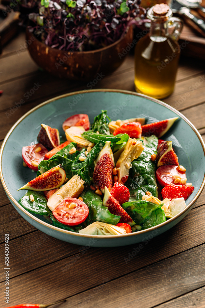 Fig and vegetables salad on the wooden background