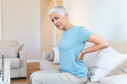 Upset mature middle aged woman feels back pain massaging aching muscles, sad senior older lady suffers from low-back lumbar pain sitting in incorrect sedentary posture, backache radiculitis concept