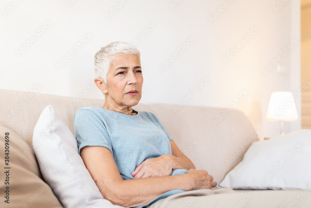 Senior woman suffering from stomach ache at home, unhappy older female sitting on bed, suffering from stomachache, food poisoning, gastritis, abdominal pain, climax Senior woman suffering from stomach ache at home, unhappy older female sitting on bed, suffering from stomachache, food poisoning, gastritis, abdominal pain, climax