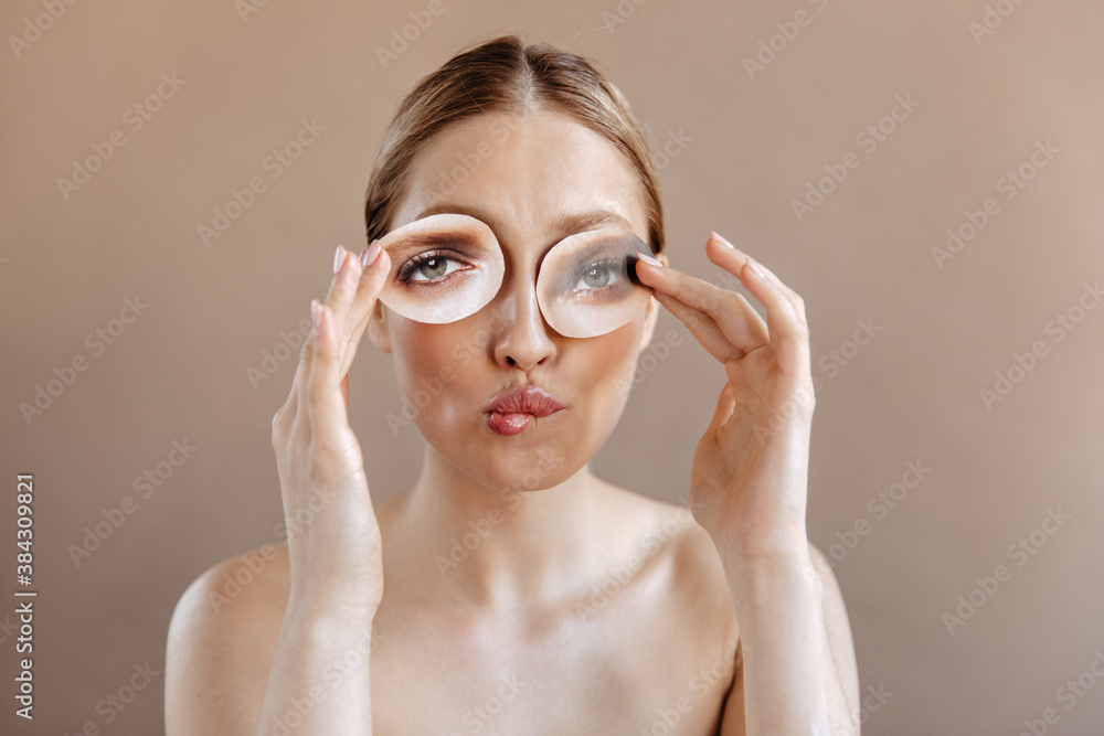 Girl without makeup bites her lip and holds photo of gray eyes, covering her face Girl without makeup bites her lip and holds photo of gray eyes, covering her face