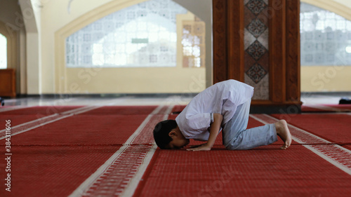 uslim boy praying in the mosque. Young Asian   muslim is on his knees praying,one of the movements in prayer, muslim people called Solat or Shalat. photo