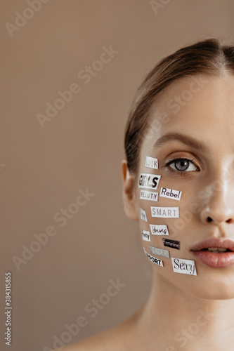 Shot of half face of gray-eyed girl with stickers-words on skin