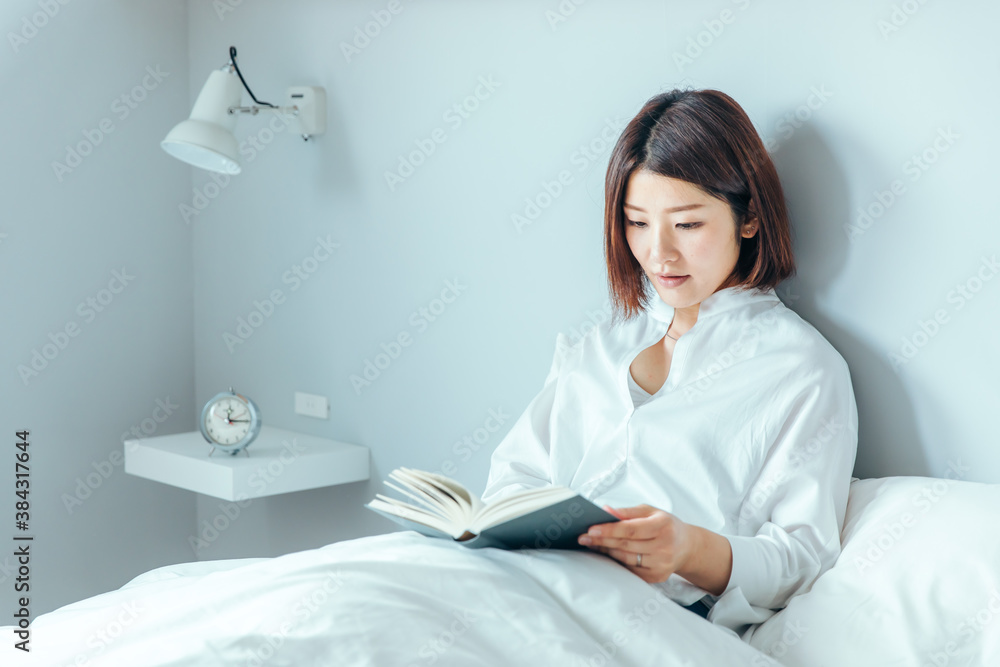 綺麗な爽やかな白い部屋に女性がベッドで読書している bed morning 綺麗な爽やかな白い部屋に女性がベッドで読書している bed morning