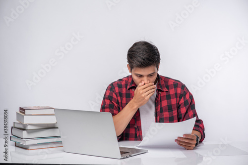 A man using a laptop in the office and doing a document analysis.