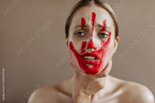 Woman with bloody trace on her face is crying from violence and fact that she is taken by throat