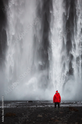 Red clothed man standing in front of water wall of the famous Icelandic waterfall called Seljalandsfoss. View to your calendar or postcard.