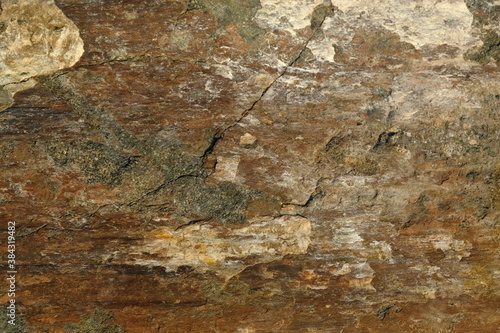 Background from a stone of igneous rock. Wallpaper made of textures of boulders of volcanic origin. Surface of granite, diabase, gabbro interspersed with spar, quartz. Sea shore. Day. Georgia.