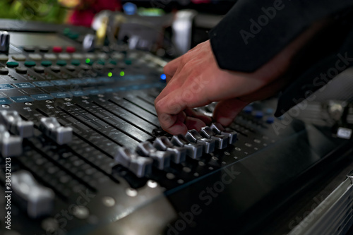 Close-up of hands adjusting sound on music controller. Sound music equalizer mixer control. Musical instruments and equipment. Selective focus.