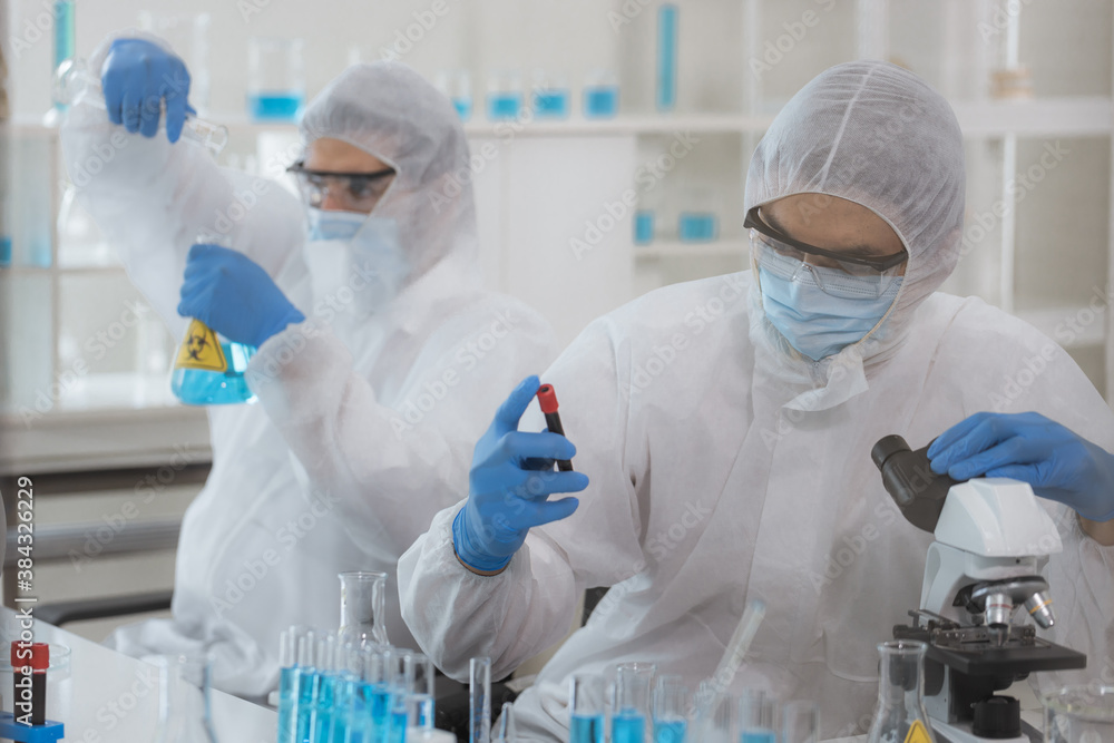 Health care researchers working in life science laboratory. Male research scientist and supervisor preparing and analyzing microscope slides in research lab. Invention of the coronavirus vaccine Health care researchers working in life science laboratory. Male research scientist and supervisor preparing and analyzing microscope slides in research lab. Invention of the coronavirus vaccine