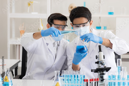 Health care researchers working in life science laboratory. Male research scientist and supervisor preparing and analyzing microscope slides in research lab. Invention of the coronavirus vaccine