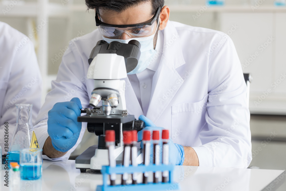 Health care researchers working in life science laboratory. Male research scientist and supervisor preparing and analyzing microscope slides in research lab. Invention of the coronavirus vaccine Health care researchers working in life science laboratory. Male research scientist and supervisor preparing and analyzing microscope slides in research lab. Invention of the coronavirus vaccine