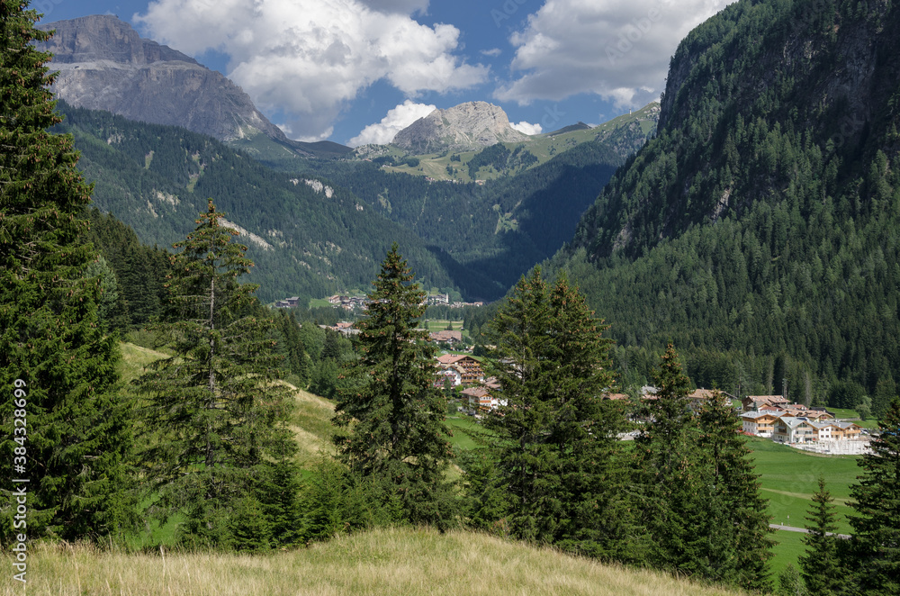 Campitello di Fassa village with Sella mountain group and Sassopiatto massif as seen from Dona valley, just before joining Fassa valley below, Dolomites, Trentino, Alto-Adige, South Tirol, Italy.