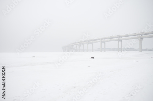 Empty overpass highway in snow, a white pure picture of snowy road. Cold winter, white snowy sky and tall highway abandoned scary with no cars © avelrouge
