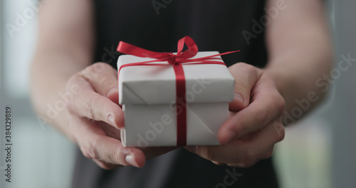 young man show white paper gift box with red ribbon