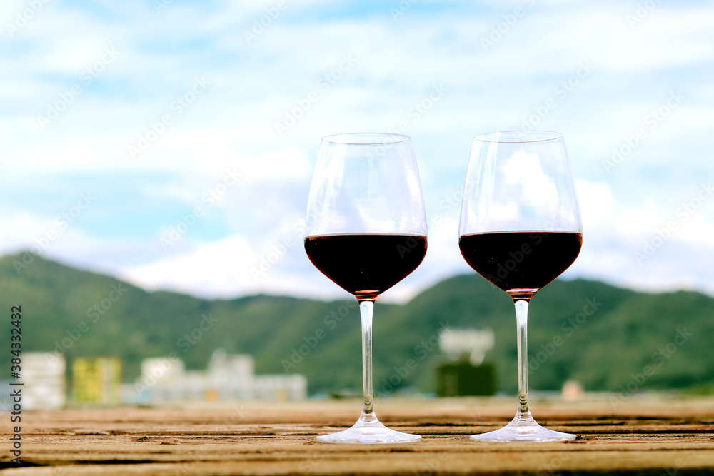 Red wine glass  on old wooden floor Mountain view background.