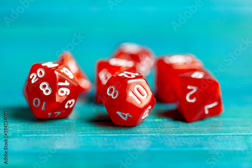 Simple red RPG board game dice set. Multiple role playing game polyhedral dice laying on the table, blue background. Tabletop games accessories, chances and randomness, luck abstract concept