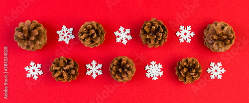Top view of New Year ornament made of white snowflakes Banner and pine cones on colorful background. Winter holiday concept with empty space for your design
