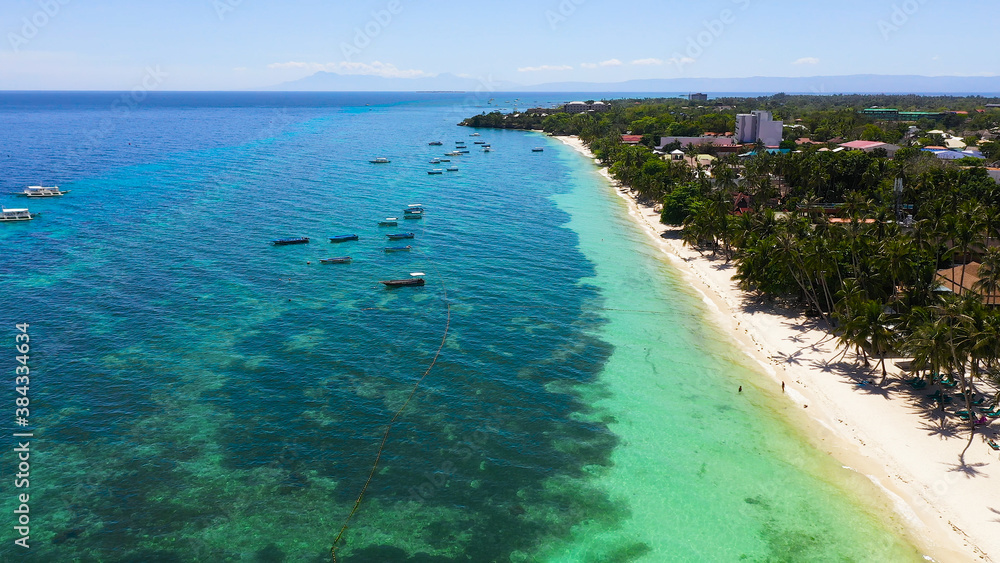 Tropical sandy beach with palm trees and turquoise clear waters. Alona beach, Panglao island, Philippines.