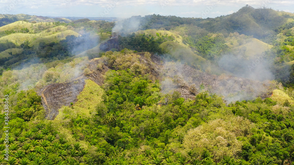 Aerial drone of Fire on hills with tropical vegetation. Farmers started a fire to expand their land. Bohol,Philippines.