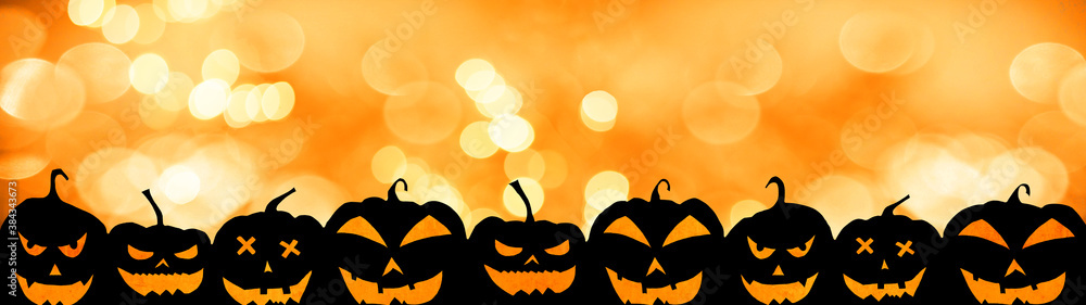 HALLOWEEN background banner wide panoramic panorama template -Silhouette of scary carved luminous cartoon pumpkins and spiders isolated on orange night texture with bokeh