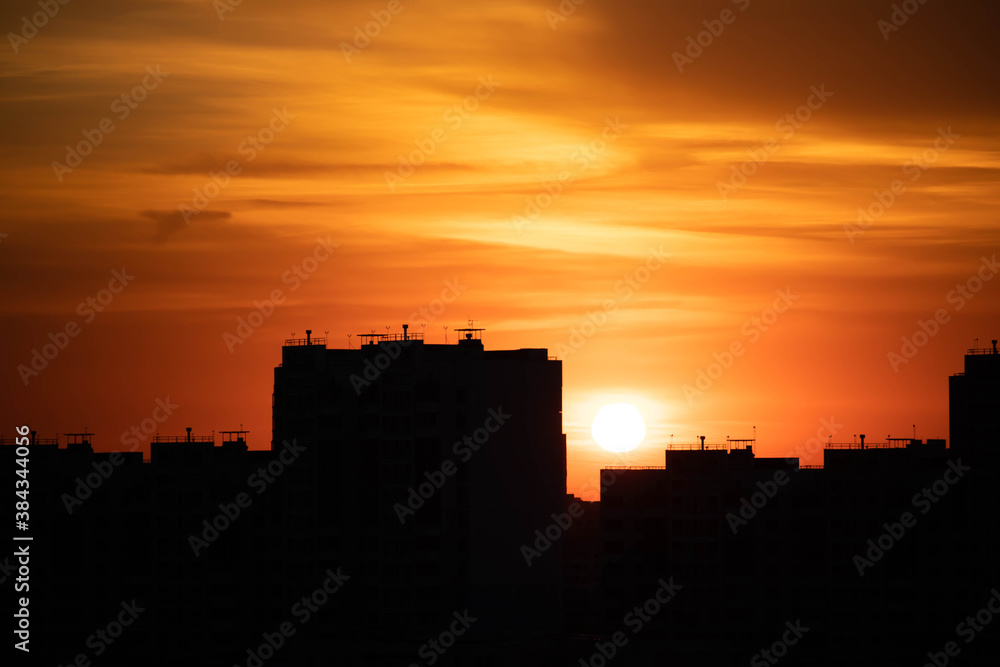 Big city in the rays of the sunset. High-rise black houses and red fiery sky.