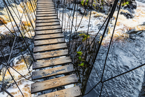 Suspension bridge and the cascades of Akhvenkoski waterfalls on the Tokhmayoki River, a popular tourist attraction situated near the settlement Ruskeala in Karelia, Russia photo