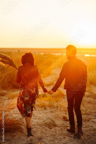 Romantic couple enjoying beautiful sunset walk on the beach travel autumn vacation. Enjoying time together. The concept of youth, love and lifestyle.