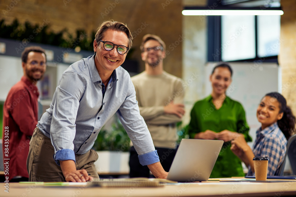 Group of young successful multi ethnic business team looking at camera and smiling while having a meeting in the modern office and coworking space Group of young successful multi ethnic business team looking at camera and smiling while having a meeting in the modern office and coworking space