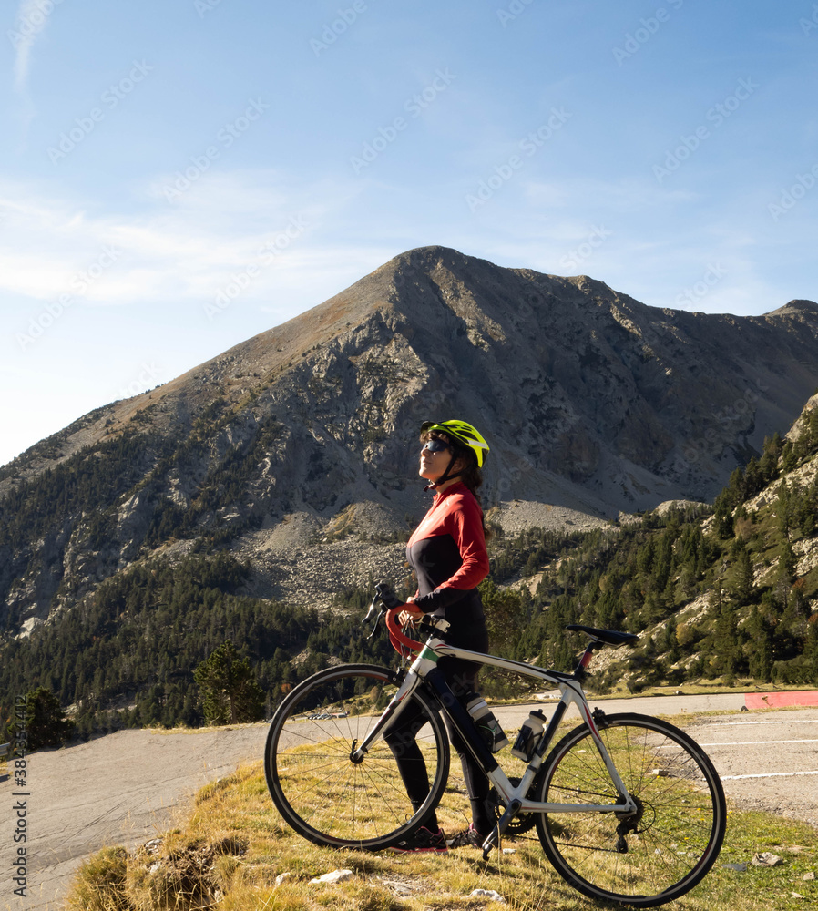 Woman road cyclist with her bike observing the mountain in the pyrenees