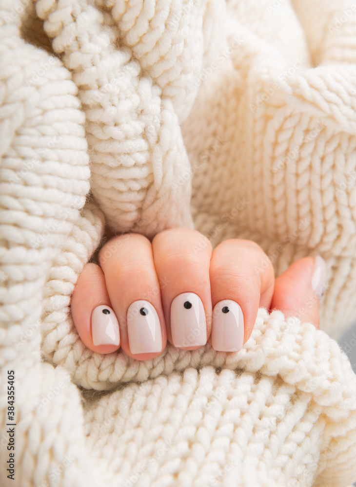 Stylish beige Nails with dots holding knitted wool material. Stylish beige Nails with dots holding knitted wool material.